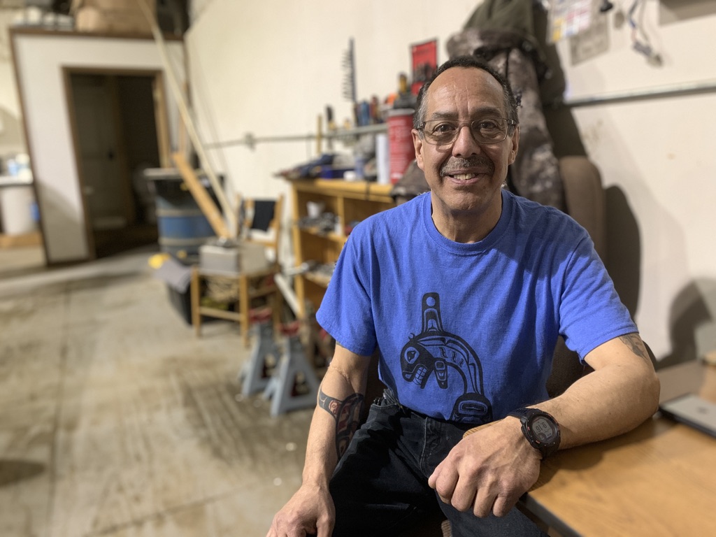 a man in a blue shirt poses for a photo inside