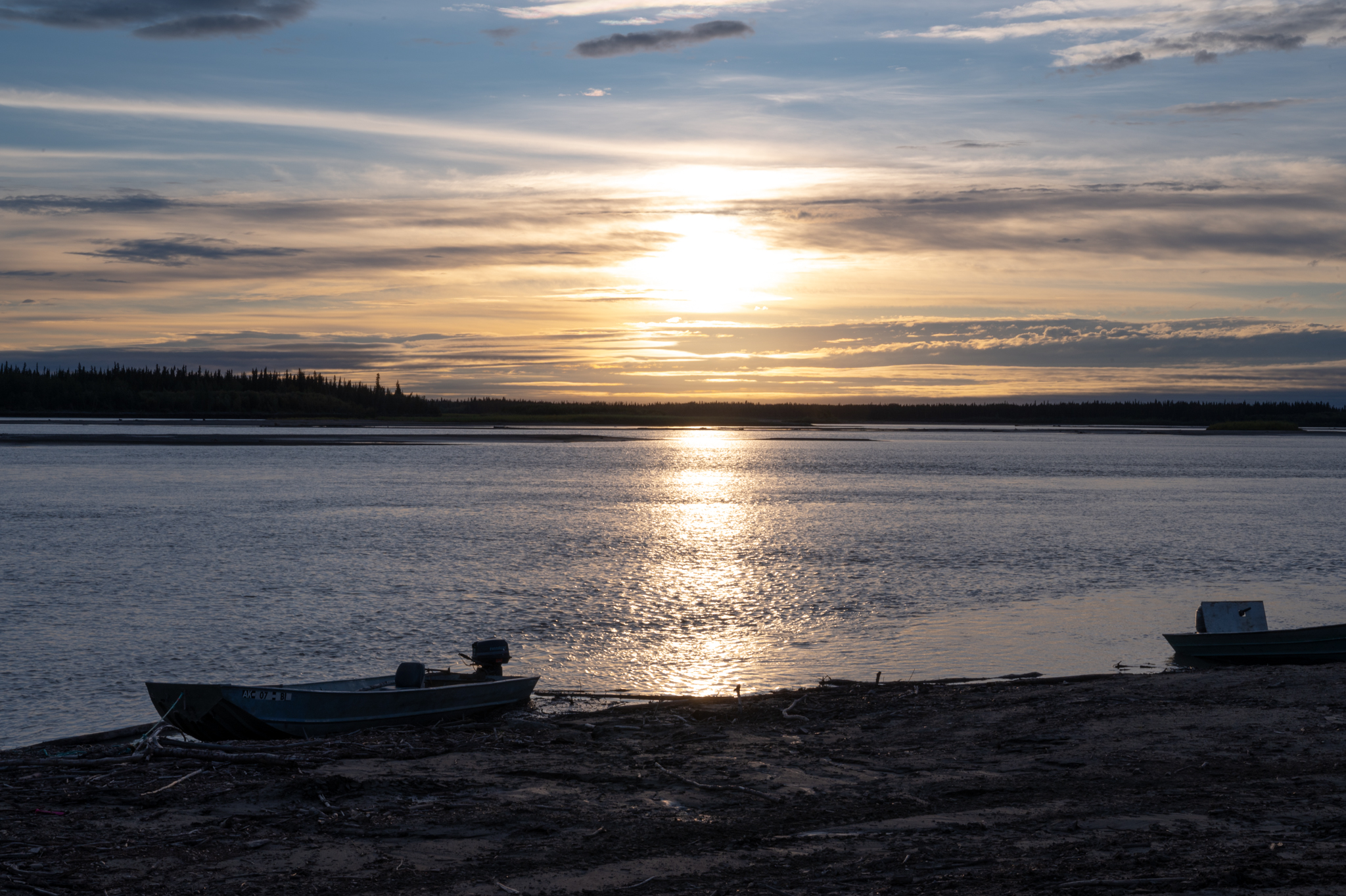 A boat next to a river with a sunset.