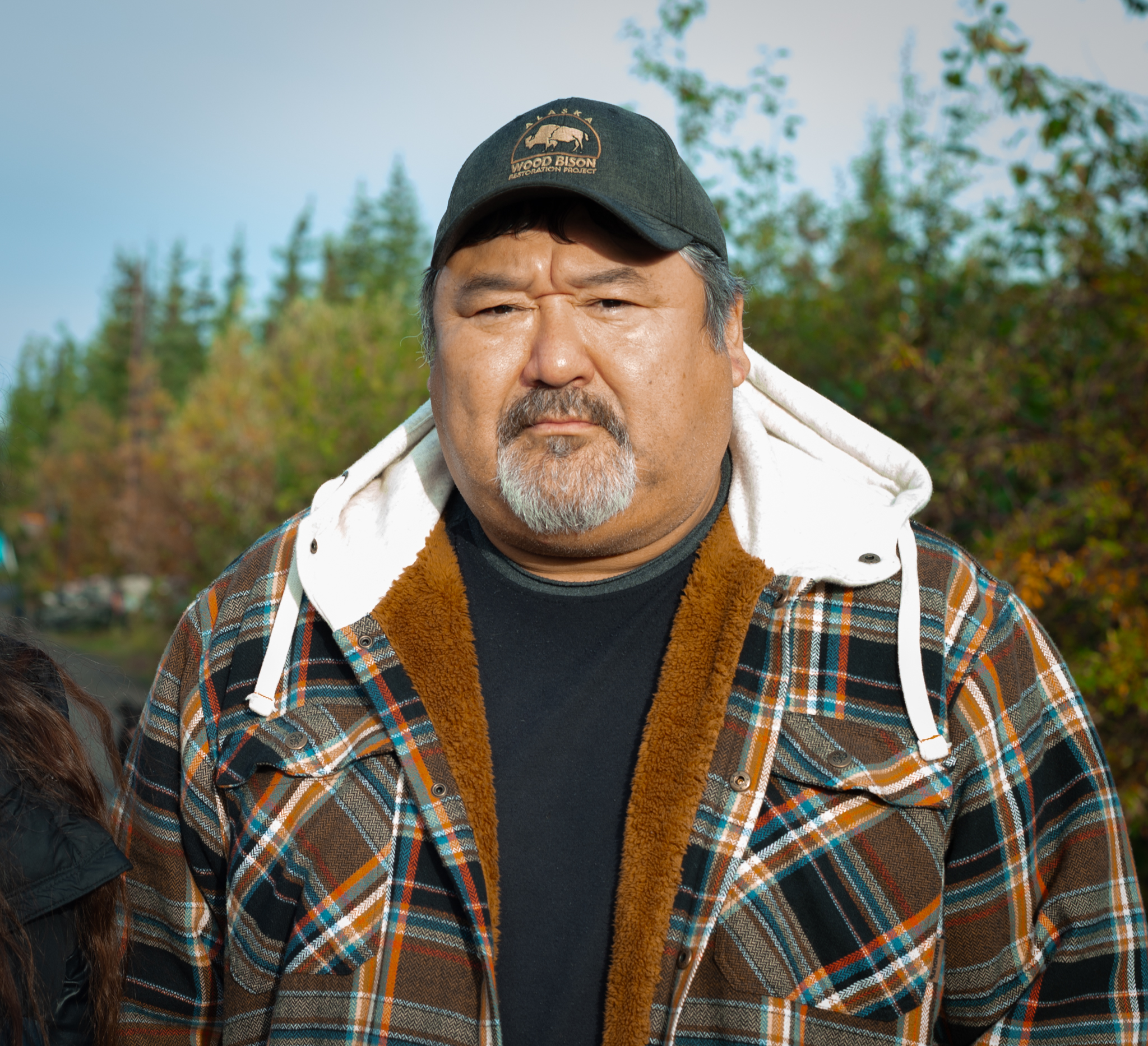 A man in a plaid jacket stands in the road.