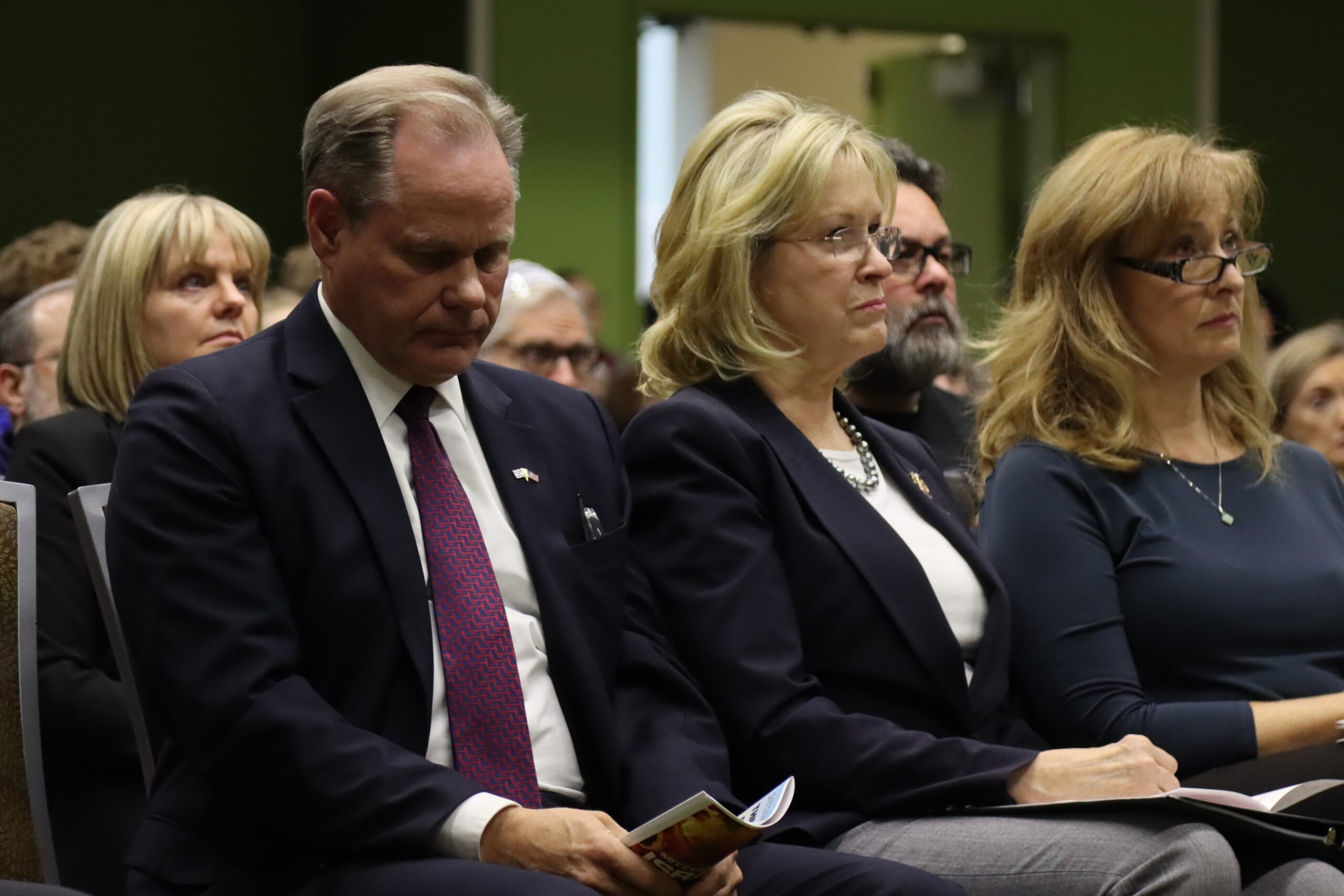 people in formal clothes sit and listen