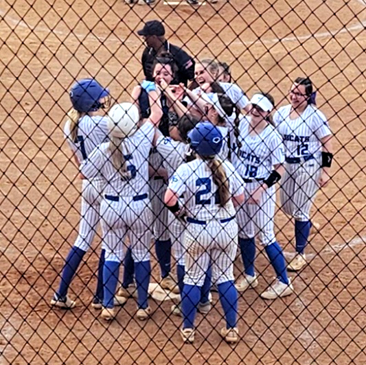 White Plains teammates mob Leighton Arnold at the plate after she hit a three-run home run Tuesday at Jacksonville. (Photo by Joe Medley)
