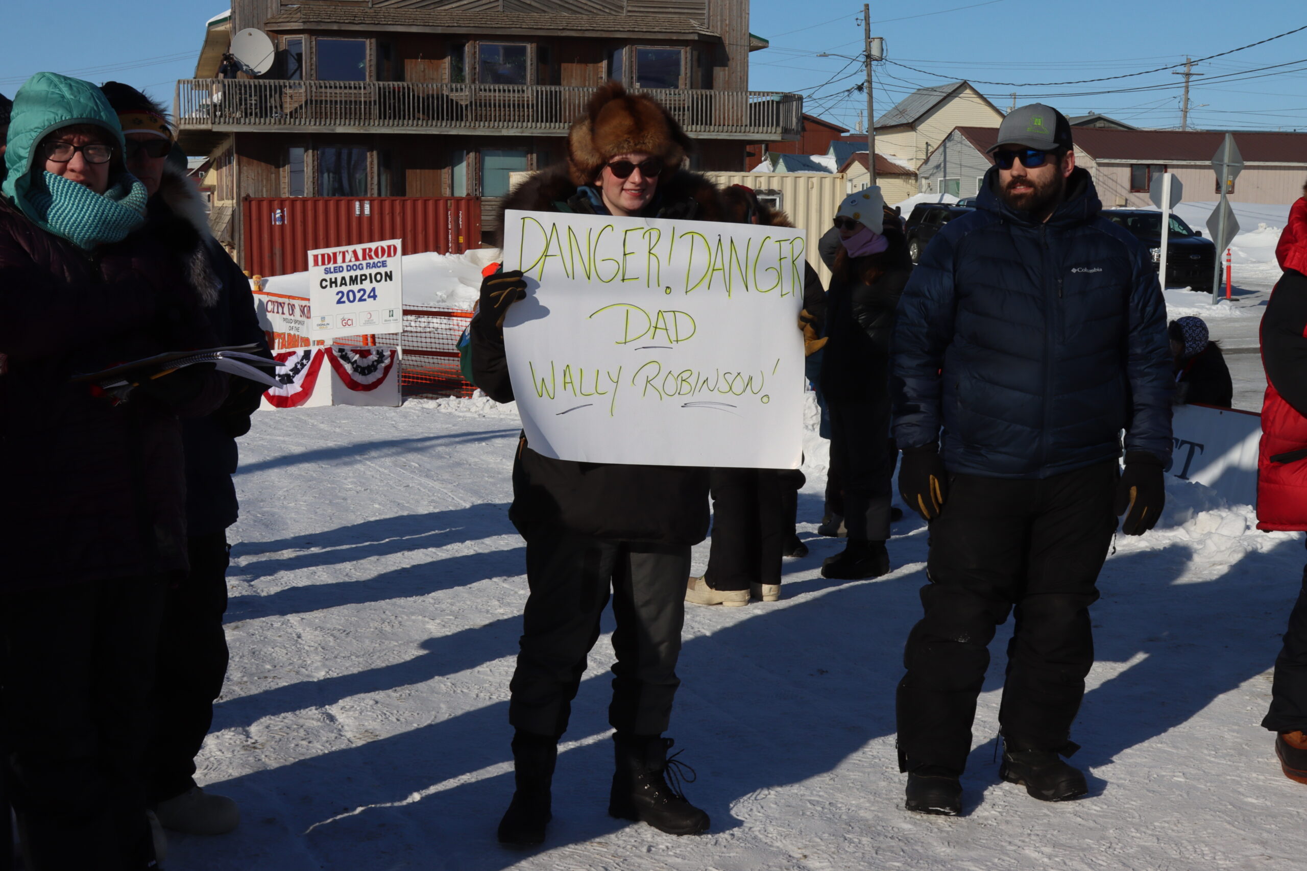 a musher holds a sign that says Danger! Danger!