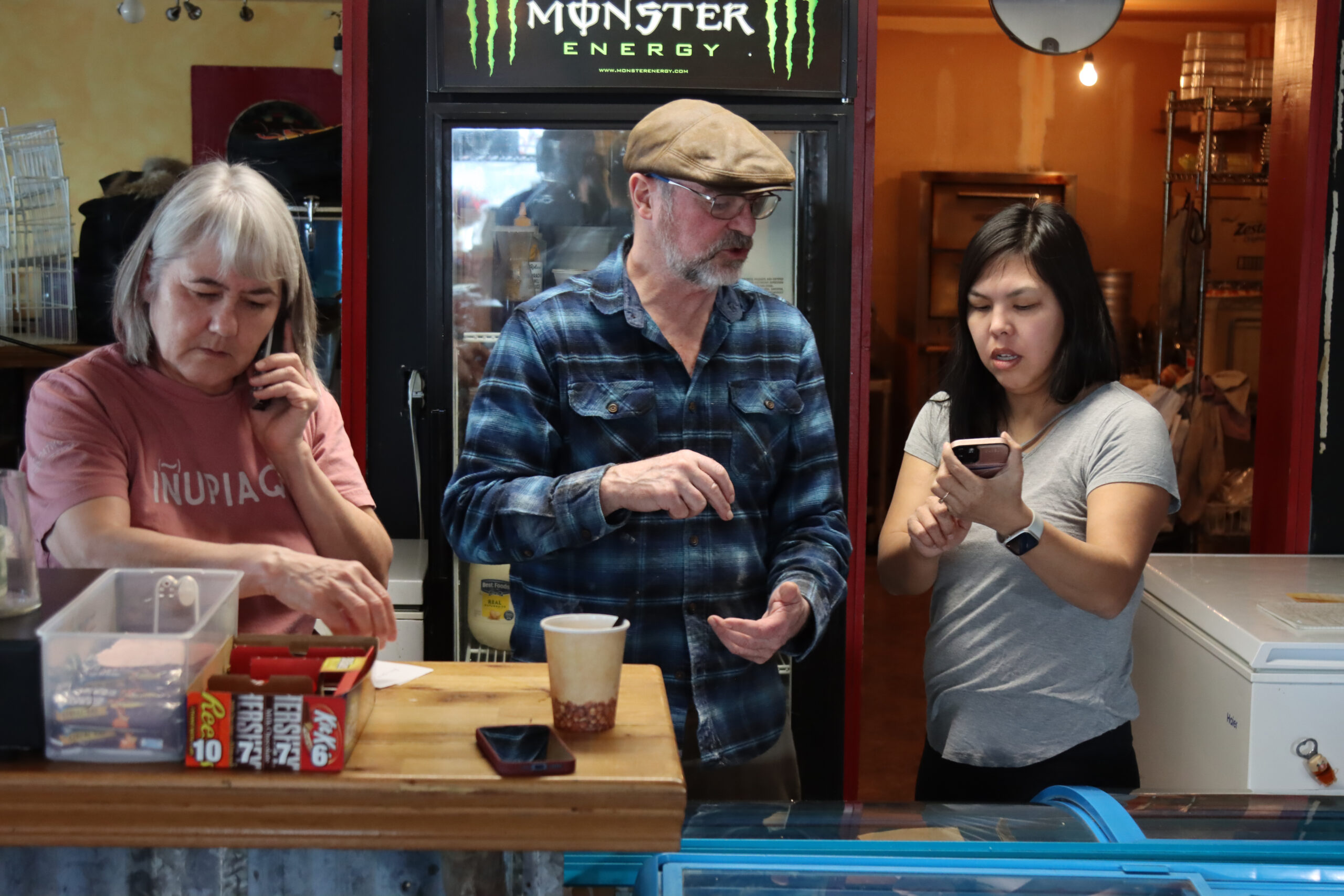 a woman is on the phone, while another two people look at a cellphone
